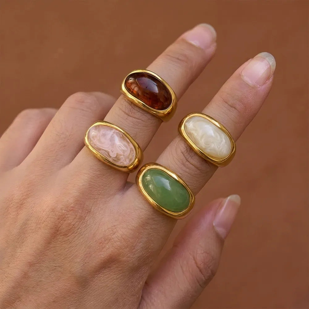 Four colorful oval statement rings worn together on a hand