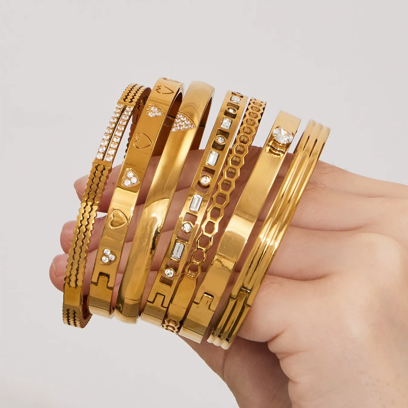 Seven hinged bangle bracelet designs displayed together in a hand