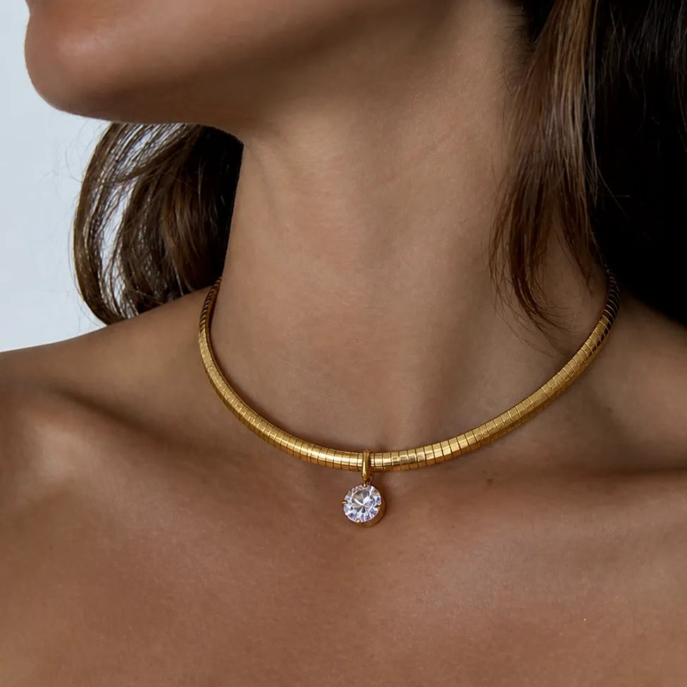 Snake chain necklace with a round clear stone pendant worn on the neck